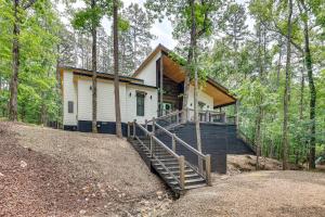 a house in the woods with a staircase leading up to it at Family-Friendly Broken Bow Home with Deck and Grill! in Broken Bow