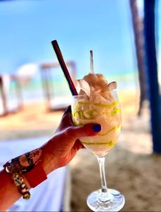 una mano sosteniendo una bebida con una pajita en Hotel Playa Paraiso en Dibulla