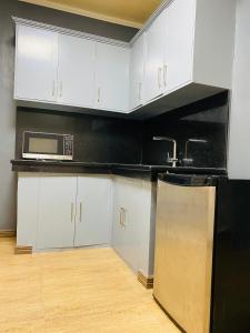 a kitchen with white cabinets and a black refrigerator at Dollosa Compound in Iba