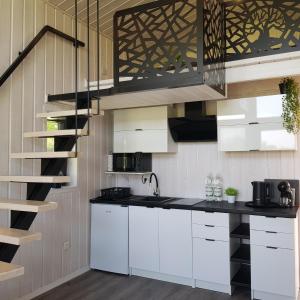 una cocina con armarios blancos y una escalera en DOMKI POD DĘBAMI , Radawa, en Radawa