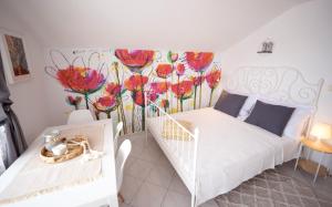 una camera da letto con un letto bianco e fiori dipinti sul muro di L'infini Sea View apartments Zubovići a Zubovići