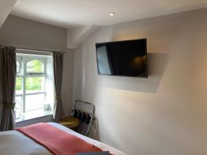 1 dormitorio con 1 cama y TV de pantalla plana en la pared en The Stork Hotel, en Lancaster