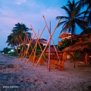 un grupo de sillas y palmeras en una playa en Hotel Playa Paraiso en Dibulla