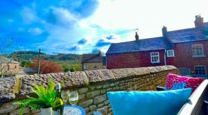 uma mesa com copos de vinho e uma parede de pedra em 3 chapel row cottages em Wirksworth