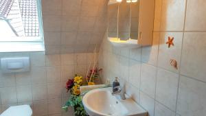 a bathroom with a sink and a mirror and flowers at Ferienwohnung am Dorfrand in Wieck