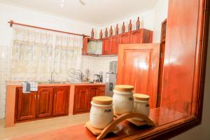 a kitchen with wooden cabinets and two jars on a counter at Stee's Cottages in Mukono
