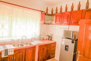 a kitchen with wooden cabinets and a sink and a window at Stee's Cottages in Mukono