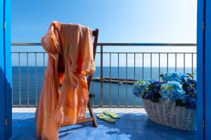 マレッティモにあるLe Conchiglieのバルコニーの椅子に座るオレンジのドレス
