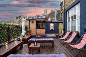 una terrazza con panche e sedie su una casa di D8 House a Londra