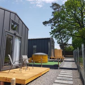 a tiny house with a deck and a patio at DOMKI POD DĘBAMI , Radawa in Radawa