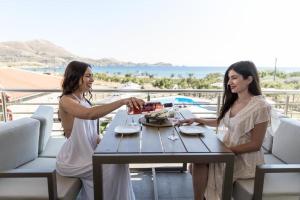two women sitting at a table with wine glasses at Costa D' Ifesto in Agios Ioannis Kaspaka