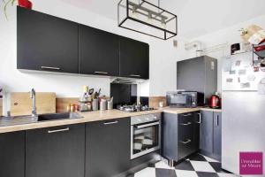 a kitchen with black cabinets and stainless steel appliances at Havre de paix in Champigny-sur-Marne