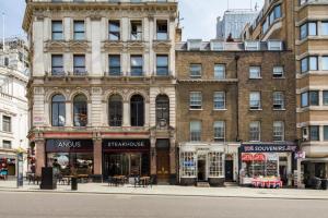 ein großes Backsteingebäude mit Tischen und Stühlen davor in der Unterkunft Imperial Piccadilly Apartments in London