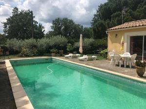 a swimming pool in a yard with a table and chairs at Gîte avec Piscine au cœur de la Vallée de la Cèze in Saint-Laurent-de-Carnols