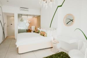 a white bedroom with a white couch and a mirror at Alpine Attitude Boutique Hotel & Conference Venue in Pretoria