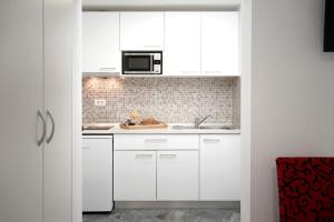 a kitchen with white cabinets and a microwave at Central Eden - ZF Hvar in Hvar