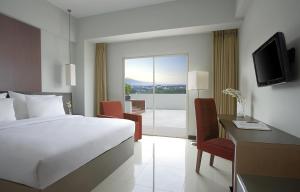 a hotel room with a bed and a desk and a television at Hotel Santika Palu in Palu