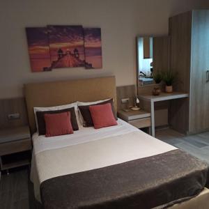ein Schlafzimmer mit einem großen Bett mit roten Kissen in der Unterkunft Achlia Beach Apartments 2 in Achlia