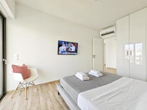 a white bedroom with a bed and a chair at Costa Alimos by Verde Apartments in Athens