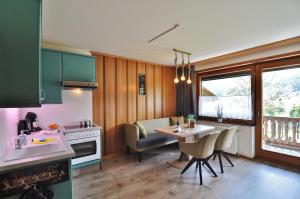 una cucina con armadi verdi e un tavolo con sedie di Pension & Apartments Weissbriach a Weissbriach