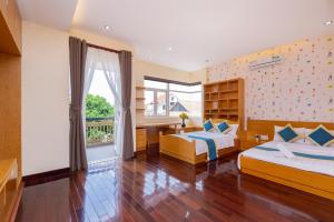 a bedroom with two beds and a desk and a window at Lê Ngọc Hân in Vung Tau