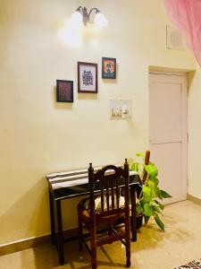 una silla en una habitación con una mesa y una planta en Crossroads Hostel 1980 en Mysore