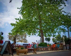 a group of tables and chairs under a tree at Arriba Apartments in Afissos