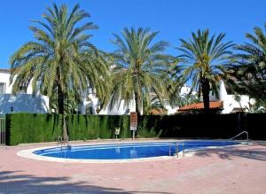 una piscina con palme sullo sfondo di En Denia, urbanización el palmar con piscina, toboganes y chiringuito a Denia