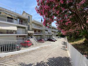 an apartment building with a parking lot with pink flowers at Basileia's Home in Paleo Tsifliki