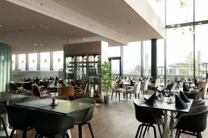 a restaurant with tables and chairs and windows at Scandic Fornebu in Fornebu