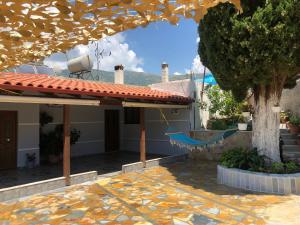 een huis met een boom en een hangmat in een tuin bij Kiparissi Guesthouse in Himare