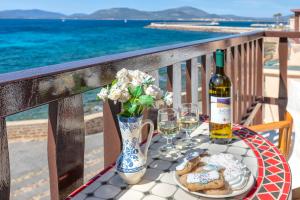 a table with a bottle of wine and wine glasses at Alguerhome Casa Blu sea view in Alghero