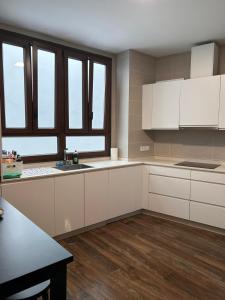 Una cocina con gabinetes blancos, una mesa y ventanas. en Moratin n3 apartamento 150m2 en el centro, en Sevilla