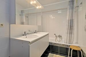 a white bathroom with a sink and a tub at Ruytingen C2 in Wenduine