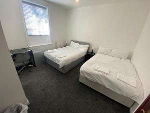 a bedroom with two beds and a desk and a window at Seaside Hotel in Brighton & Hove