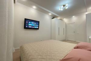 1 dormitorio con 1 cama y TV en la pared en Nova Center - SQ en Taldykolʼ