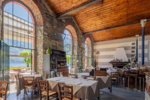 ein Restaurant mit Tischen und Stühlen und großen Fenstern in der Unterkunft La Locanda del Cantiere in Laglio