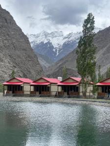 a building with red roofs next to a body of water at Dream Nest Resort in Skardu