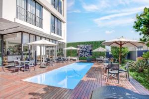 a pool with chairs and umbrellas next to a building at Urban Oasis Apartments at One Hyde Park in Johannesburg