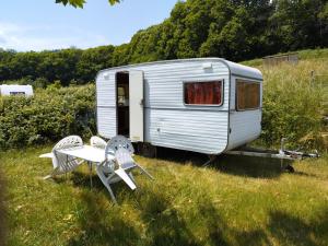 remolque blanco con mesa y sillas en un campo en Camping La Fôret du Morvan Vintage caravan, en Larochemillay