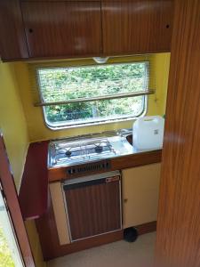 a small kitchen with a stove and a window at Camping La Fôret du Morvan Vintage caravan in Larochemillay