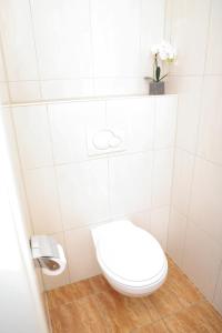 a white bathroom with a toilet and a vase of flowers at Art & Nature Apartments in der Nähe FFM-Messe in Bad Vilbel