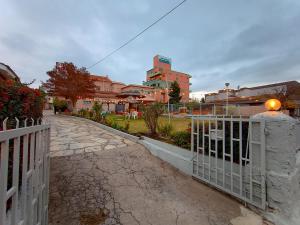 a white fence next to a street with a building at Nuevo Suiza Hotel in Villa Carlos Paz