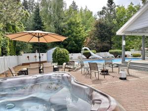 a swimming pool with a hot tub and an umbrella at All Seasons Getaway by NW Comfy Cabins in Leavenworth