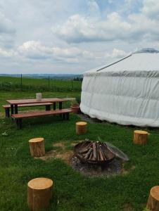 uma tenda com uma mesa de piquenique, uma mesa e troncos em Jurta na zvířecí farmě 