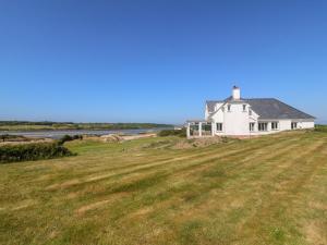 una casa blanca en una colina con un campo en Wig Carna, en Holyhead