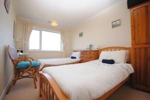 a bedroom with two beds and a chair and a window at Lifeboat View, Selsey in Selsey