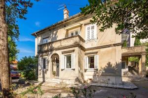 una vecchia casa in pietra con un albero di Villa Carolina a Fiume (Rijeka)