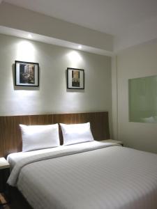 a bedroom with a large bed with white pillows at Hart Hotel Arjuna in Mataram