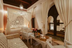 uma sala de estar com uma cama, um sofá e uma mesa em Riad Dar Dialkoum em Marrakech